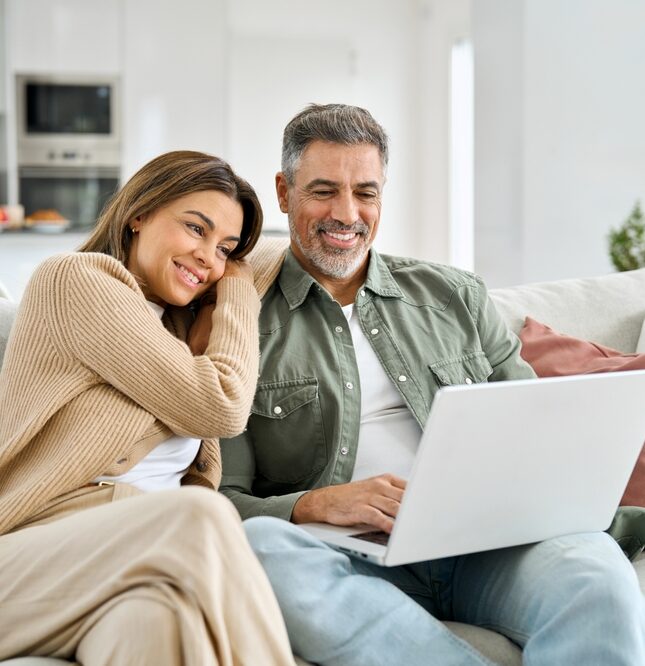 Happy,Middle,Aged,Couple,Using,Laptop,Relaxing,On,Couch